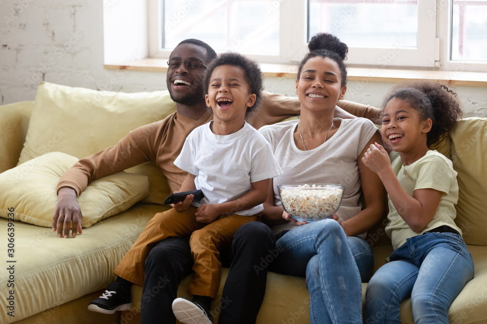 Happy biracial family with kids watching TV together