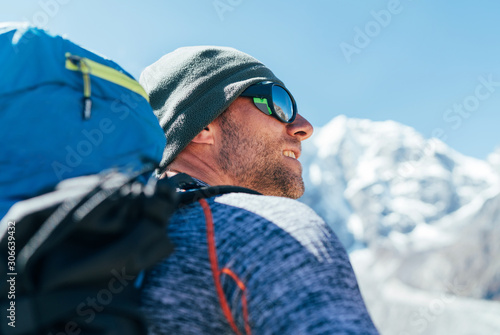 Portrait of unshaved Hiker man with backpack and UV protecting sunglasses on Taboche 6495m peakk background ,  He enjoying mountain views during Everest Base Camp trekking route. photo