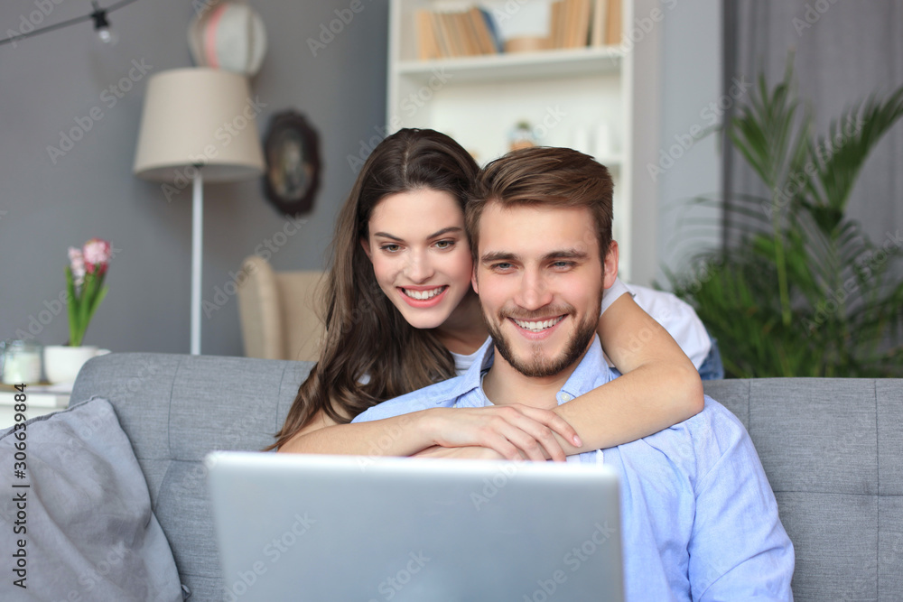 Young couple doing some online shopping at home, using a laptop on the sofa. Young couple doing some online shopping at home, using a laptop on the sofa.
