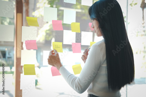 businesswoman woman thinking planning with adhesive notes on glass wall