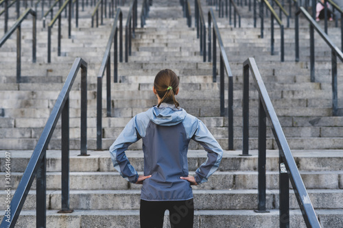 Young adult sporty woman  looking at stairs, preparing to training photo