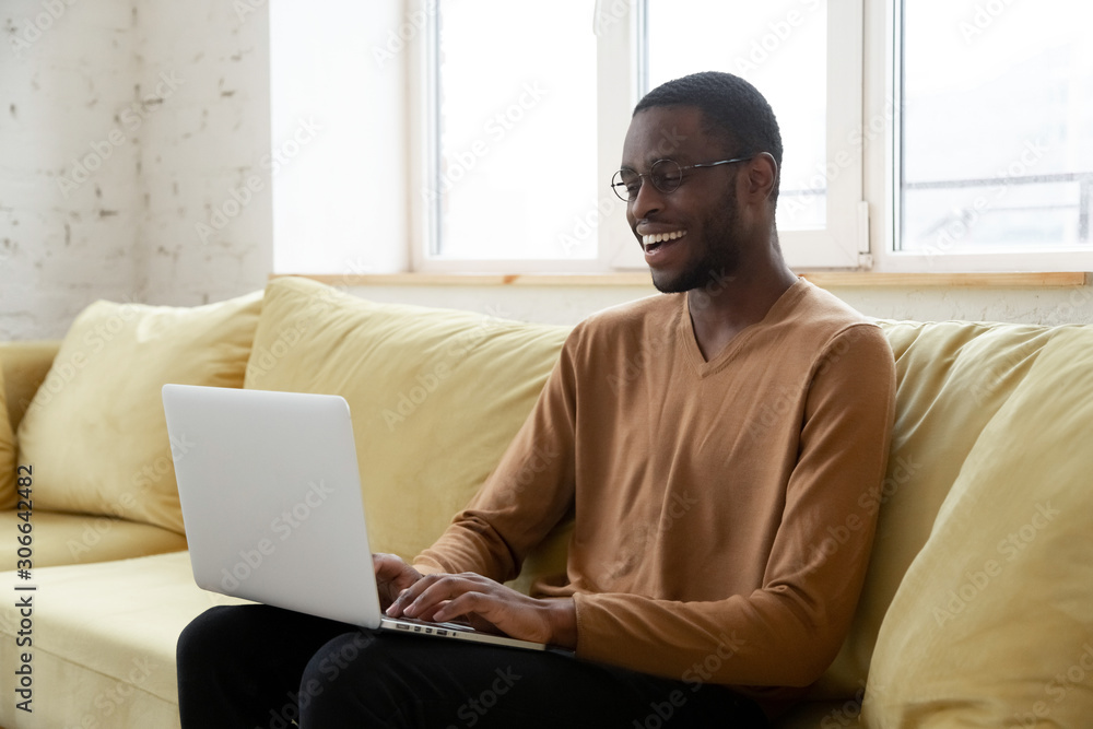 Smiling african American man using laptop in living room Smiling african American man using laptop in living room