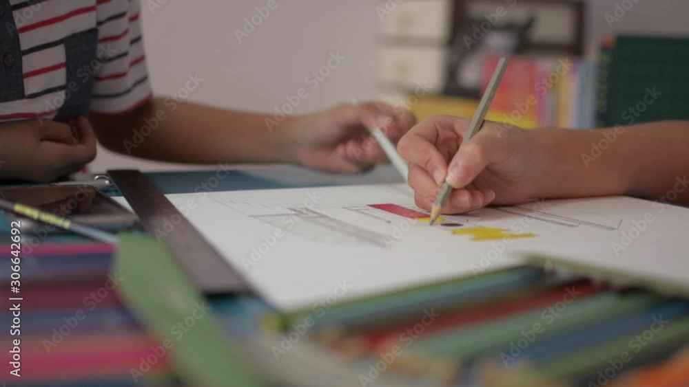 Two girls drawing on a paper and helping each other do homework on the desk at home. Education concept. Two girls drawing on a paper and helping each other do homework on the desk at home. Education concept.