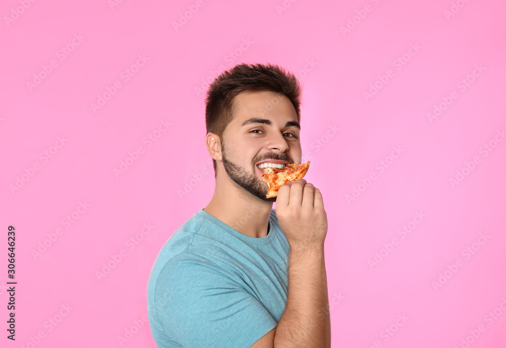 Handsome man eating pizza on pink background Handsome man eating pizza on pink background