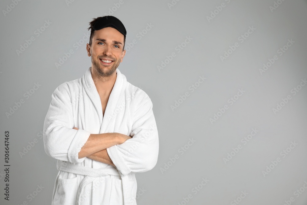 Happy young man in bathrobe on light grey background. Space for text Happy young man in bathrobe on light grey background. Space for text