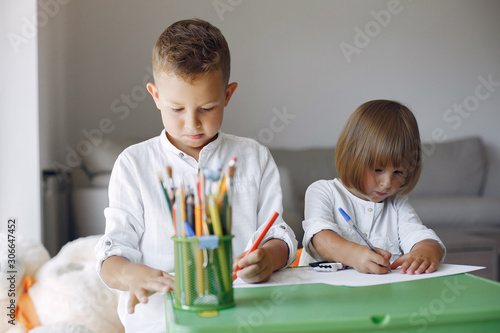 Brother and sister in a playing room. Children drawing at the table