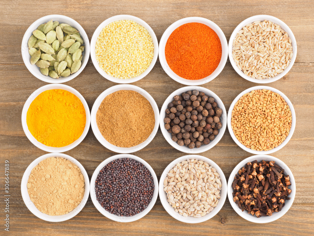 Allspice, pepper chili, fenugreek, cloves, turmeric, millet, oat, buckwheat, green cardamom, dry ginger, masala on brown wood background. Indian cuisine, ayurveda, naturopathy concept Allspice, pepper chili, fenugreek, cloves, turmeric, millet, oat, buckwheat, green cardamom, dry ginger, masala on brown wood background. Indian cuisine, ayurveda, naturopathy concept