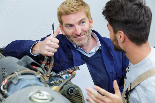 aircraft mechanical engineer giving an okay sign to apprentice