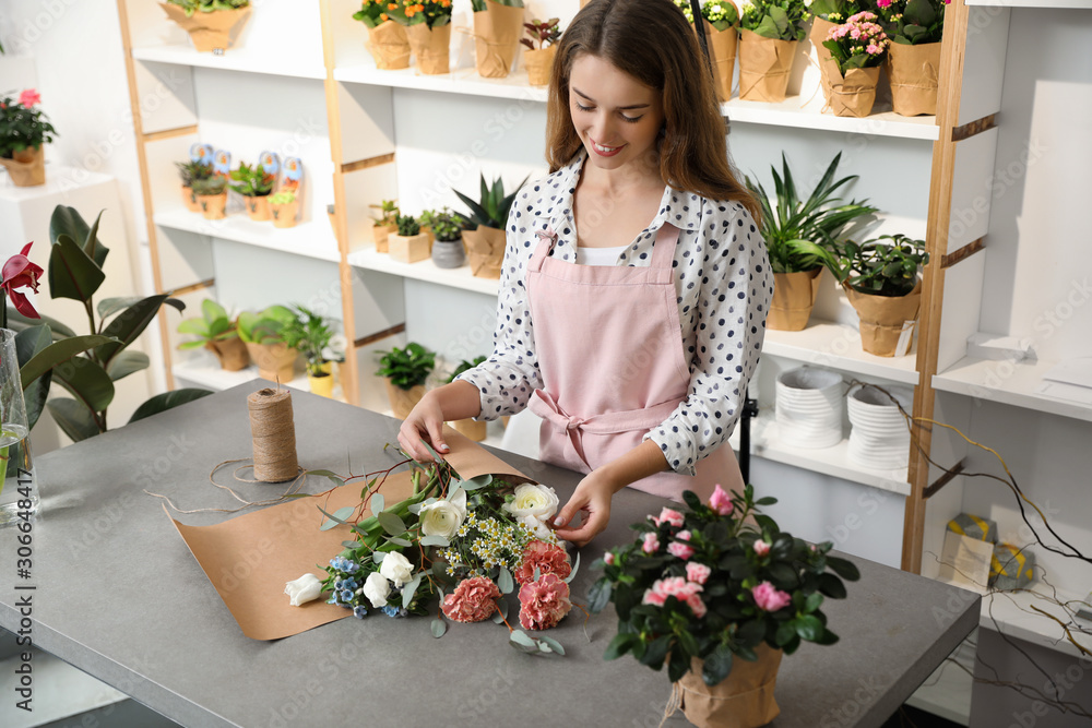 Florist making bouquet with fresh flowers at table in shop