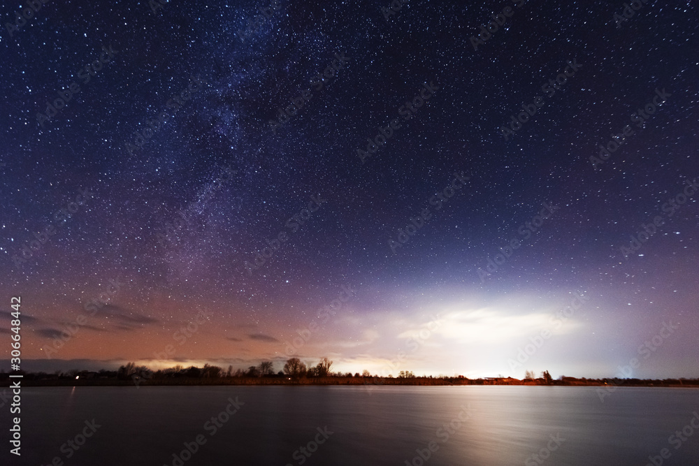 A magical starry night on the river bank with a milky way in the sky and falling stars in the winter. A magical starry night on the river bank with a milky way in the sky and falling stars in the winter.