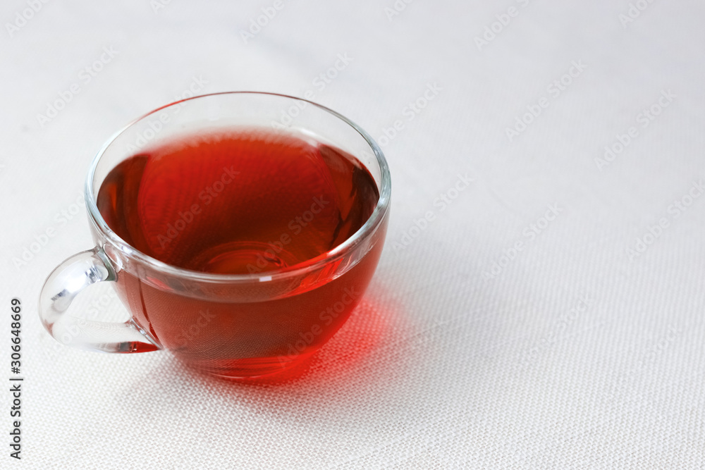red cup of tea with hibiscus on the table on a white tablecloth. Invigorating tea