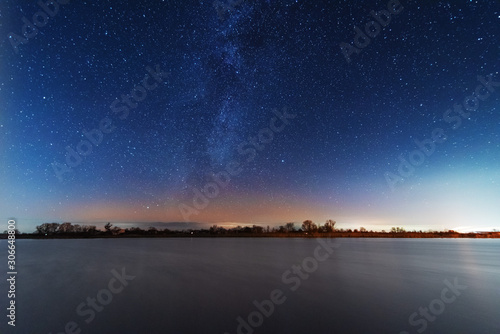 A magical starry night on the river bank with a milky way in the sky and falling stars in the winter.
