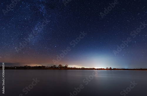A magical starry night on the river bank with a milky way in the sky and falling stars in the winter. © reme80