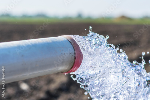 high pressure crystal bluish sweet water flushing out of an agriculture industrial tube waell in fields  