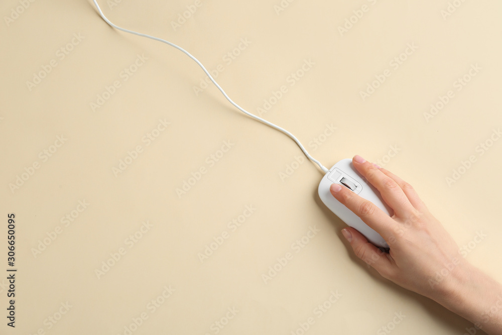 Woman using modern wired optical mouse on beige background, top view. Space for text Woman using modern wired optical mouse on beige background, top view. Space for text
