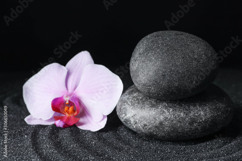 Spa stones and orchid flower on black sand with beautiful pattern. Zen concept