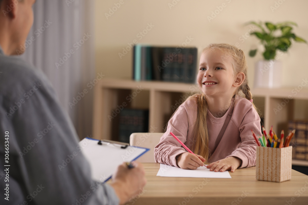 Little girl on appointment with child psychotherapist indoors Little girl on appointment with child psychotherapist indoors