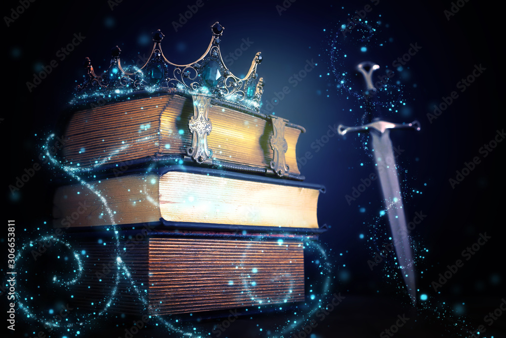 Obraz premium niski klucz obraz pięknej korony królowej / króla nad zabytkową książką i mieczem. fantasy średniowieczny okres. Selektywna ostrość