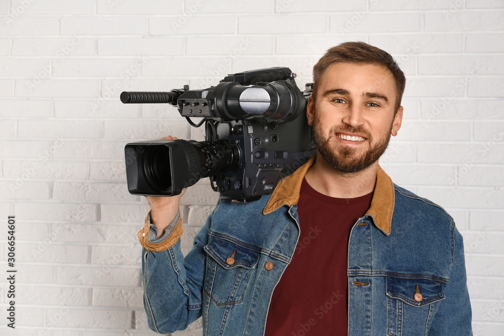 Operator with professional video camera near white brick wall Operator with professional video camera near white brick wall