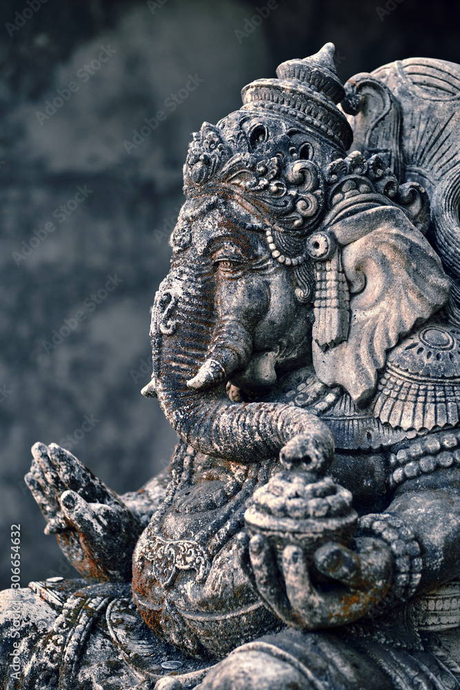 An old Asian statue of Ganesha god stands in the garden of a temple - Ubud, Bali, Indonesia.