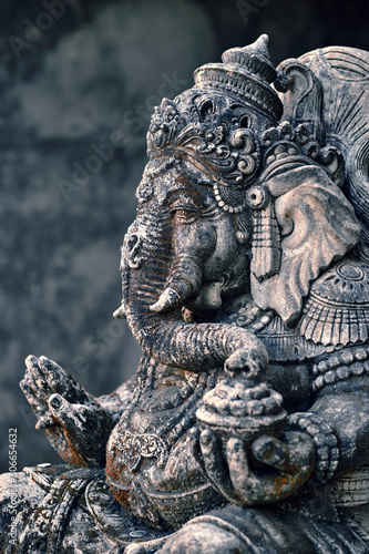 An old Asian statue of Ganesha god stands in the garden of a temple - Ubud, Bali, Indonesia. © Dmitry Yakovtsev