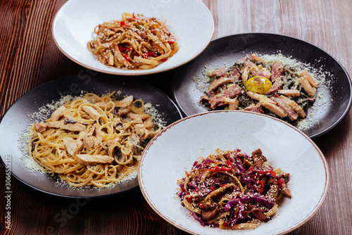 Several plates of pasta with different kinds of sauce over wooden background, top view. Concepts of Italian food.