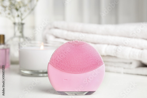 Modern face cleansing brush on white table. Cosmetic accessory