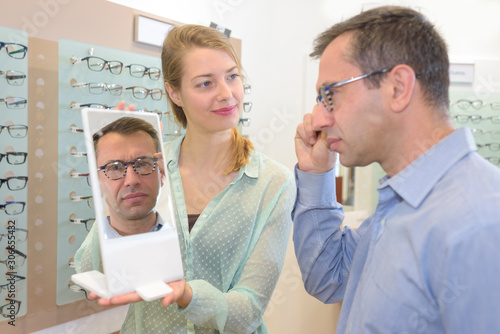 man looking at the mirror while fitting his eyeglasses