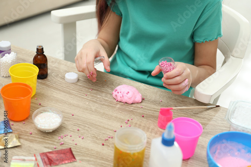 Little girl making homemade slime toy at table, closeup