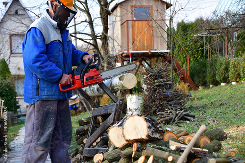 Sawing wood with chainsaw with safety glasses and helmet