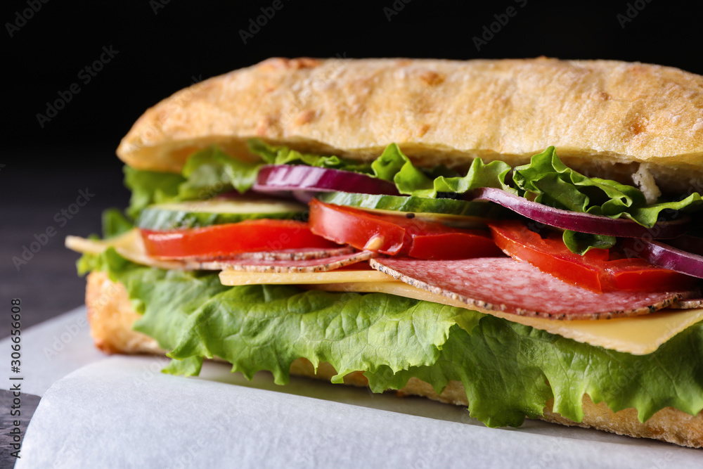 Delicious sandwich with fresh vegetables and salami on table, closeup Delicious sandwich with fresh vegetables and salami on table, closeup