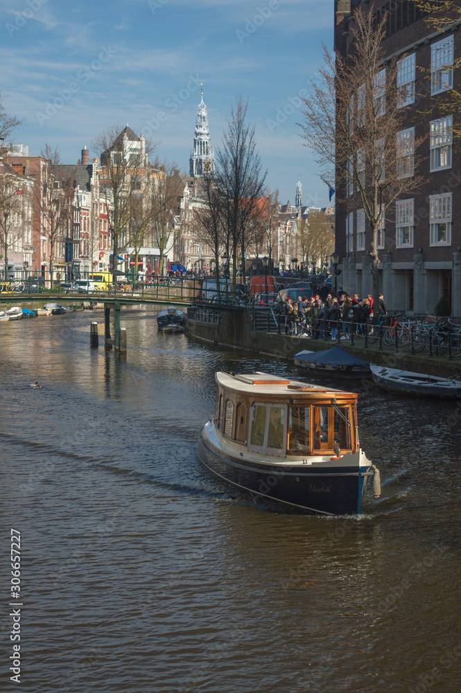 A canal boat making its way down Amsterdam canal in Winter