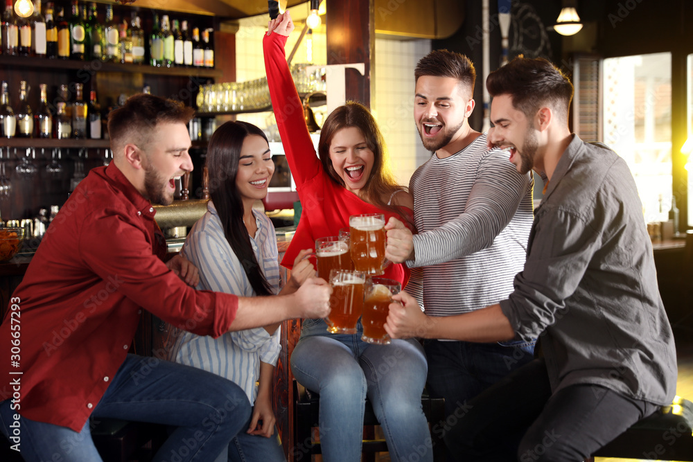 Group of friends celebrating victory of favorite football team in sport bar