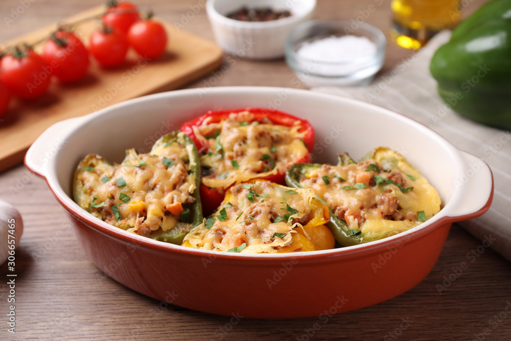 Tasty stuffed bell peppers in baking dish on wooden table Tasty stuffed bell peppers in baking dish on wooden table