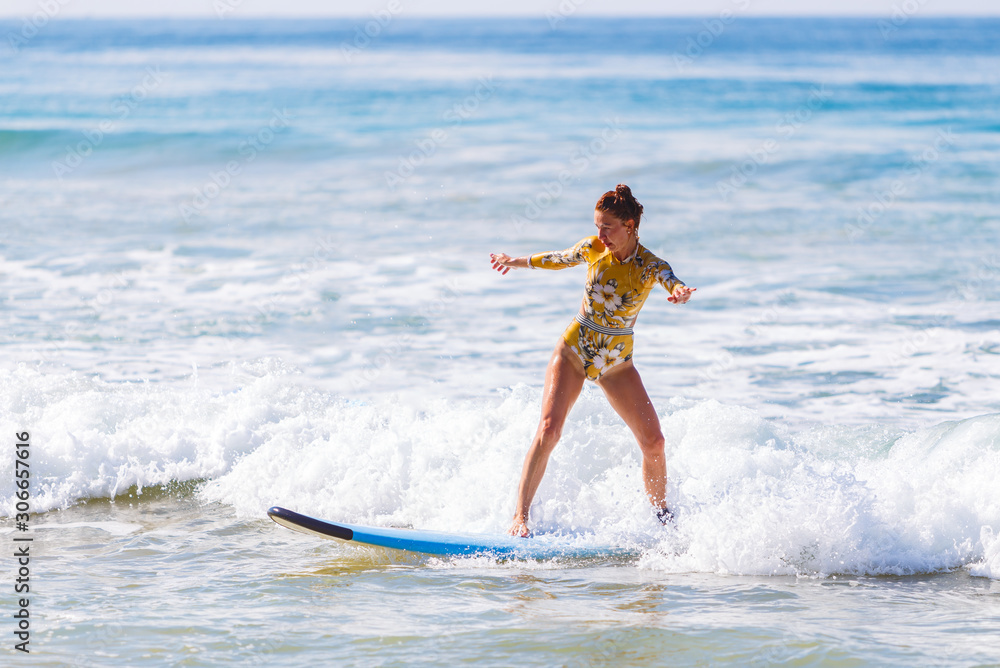 young girl rolls on surfboard, starts to learn, not a professional, against the waves of the ocean, Sri Lanka. young girl rolls on surfboard, starts to learn, not a professional, against the waves of the ocean, Sri Lanka.