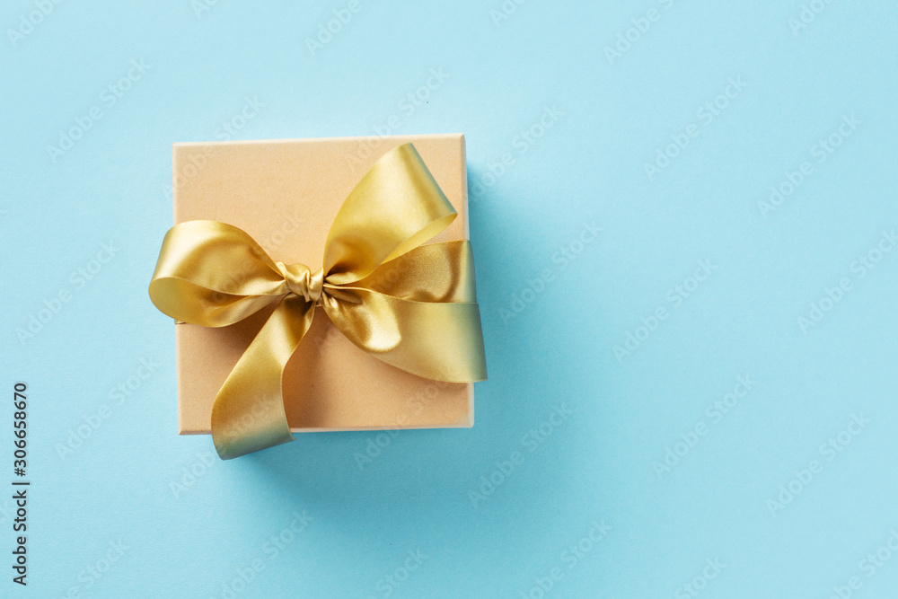 Gift box with golden ribbon on bright background Gift box with golden ribbon on bright background