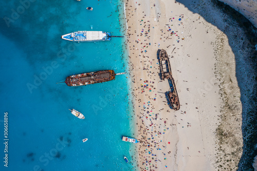 Aerial overhead drone shot of Zakynthos Navagio beach full of tourists and cruise ship in Ionian sea in Greece