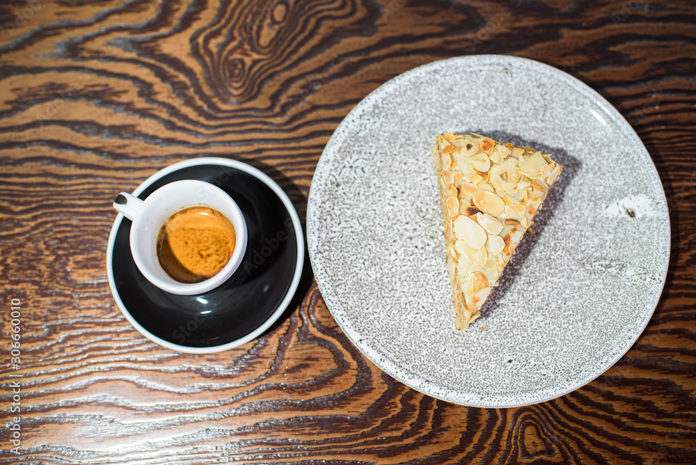 A slice of Esterhazy cake on a gray plate close-up on the table and a cup of espresso A slice of Esterhazy cake on a gray plate close-up on the table and a cup of espresso