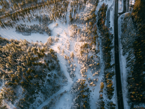 Aerial view on the road and forest at the winter time. Natural winter landscape from air. Landscape in Finland from drone