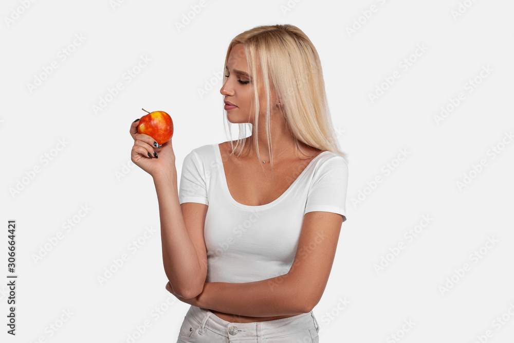 Beautyful, sexy blonde girl with perfect healthy hair and natural makeup posing in studio with an apple, young woman portrait isolated on white background Beautyful, sexy blonde girl with perfect healthy hair and natural makeup posing in studio with an apple, young woman portrait isolated on white background