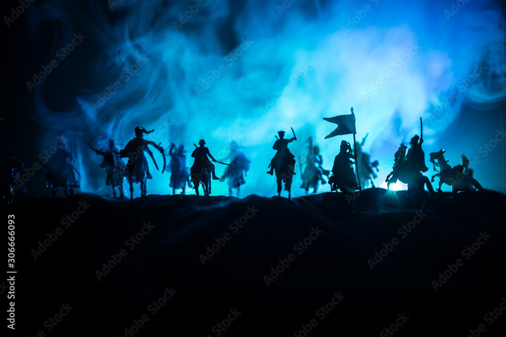 Medieval battle scene with cavalry and infantry. Silhouettes of figures as separate objects, fight between warriors on dark toned foggy background. Night scene. Medieval battle scene with cavalry and infantry. Silhouettes of figures as separate objects, fight between warriors on dark toned foggy background. Night scene.