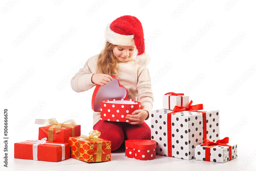 Cute girl in santa claus hat opens christmas presents. Isolated on the white Cute girl in santa claus hat opens christmas presents. Isolated on the white
