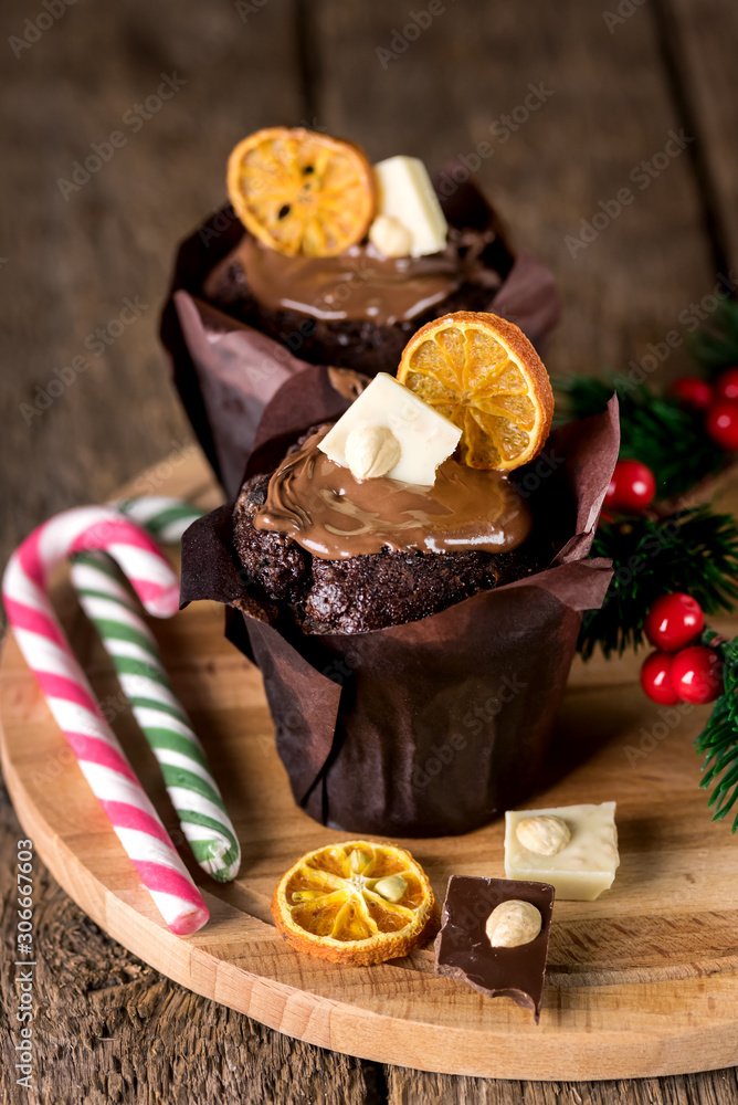 Two Tasty Homemade Chocolate Muffins Decorated with Citrus Chips and White Chocolate on Wooden Tray Two Candy Canes Christmas Dessert Food Vertical