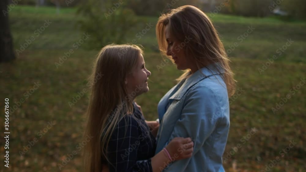 Mother and daughter are hugging in the evening park for a walk. Schoolgirl daughter and young mother. Mothers Day, single parent Mother and daughter are hugging in the evening park for a walk. Schoolgirl daughter and young mother. Mothers Day, single parent