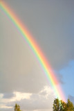 Rainbow on cloudy grey and blue sky background