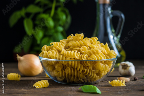 Canvas Print raw ingredients fusilli pasta in glass bowl onion fresh basil olive oil bottle g