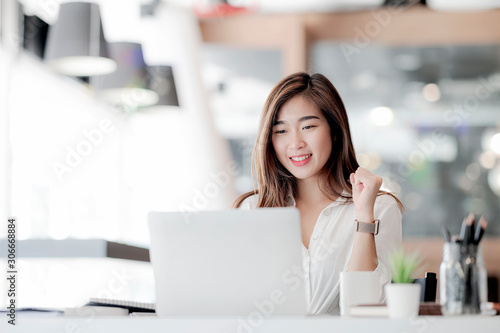 Businesswoman working with laptop with happiness at office.
