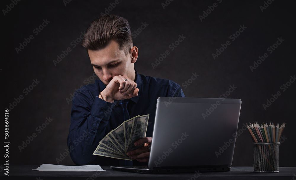 Successful business man on a dark background with laptop and money. Bank Sales Manager Successful business man on a dark background with laptop and money. Bank Sales Manager