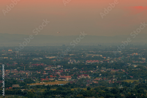 Blurry high angle nature background, which can see distant views (houses, mountains, trees, roads). The atmosphere is surrounded by the wind blowing through, seen at the natural viewpoint on the way. © bangprik