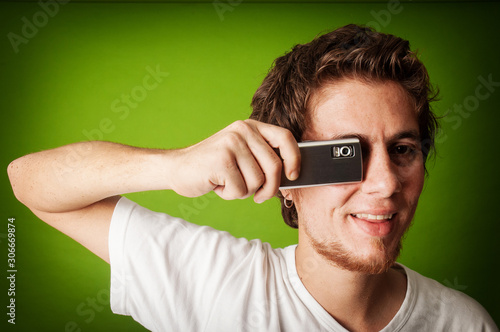 young man looking behind the cell phone